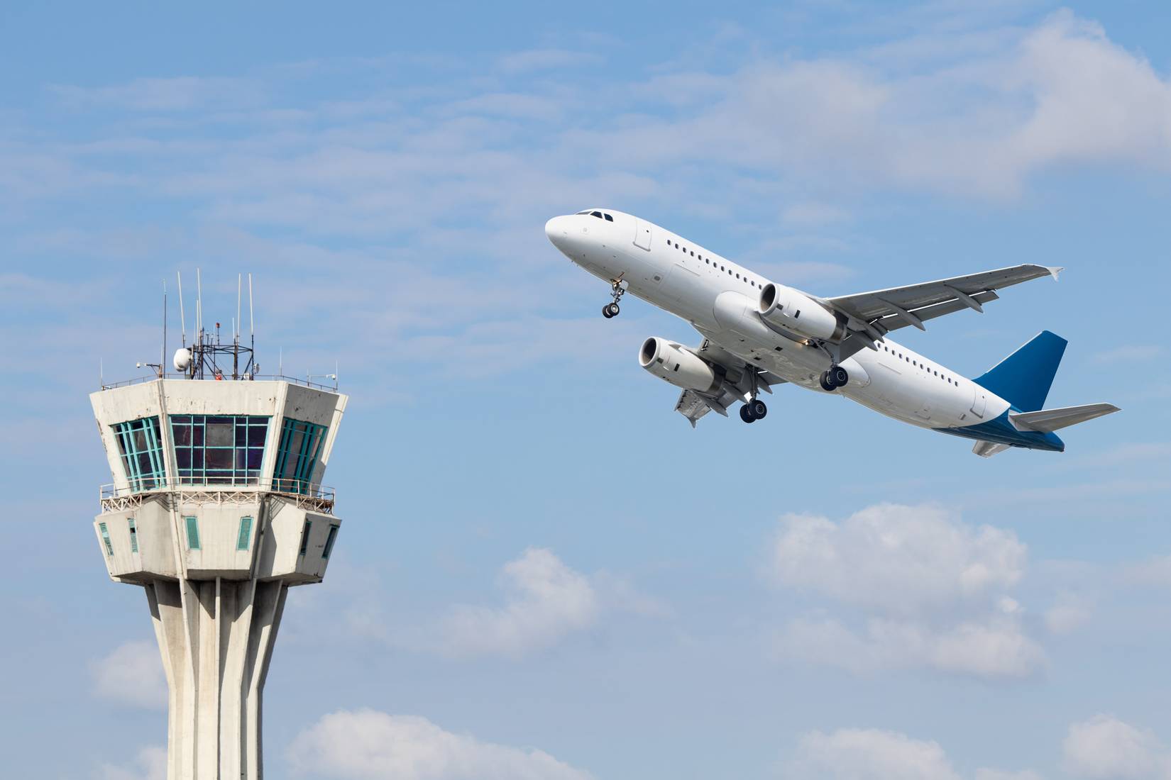 Air control tower and airplane on blue and cloudy sky background.