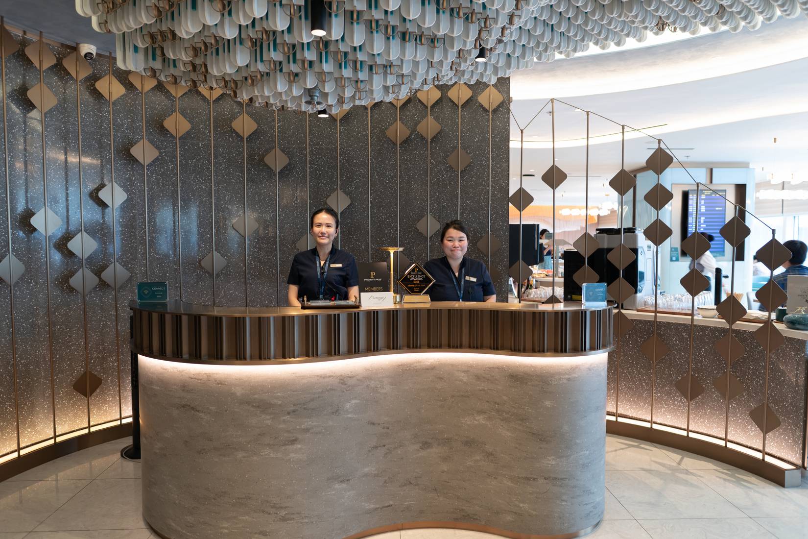 The reception desk of the Kyra Lounge is seen with two staff members and a Priority Pass Excellence Awards