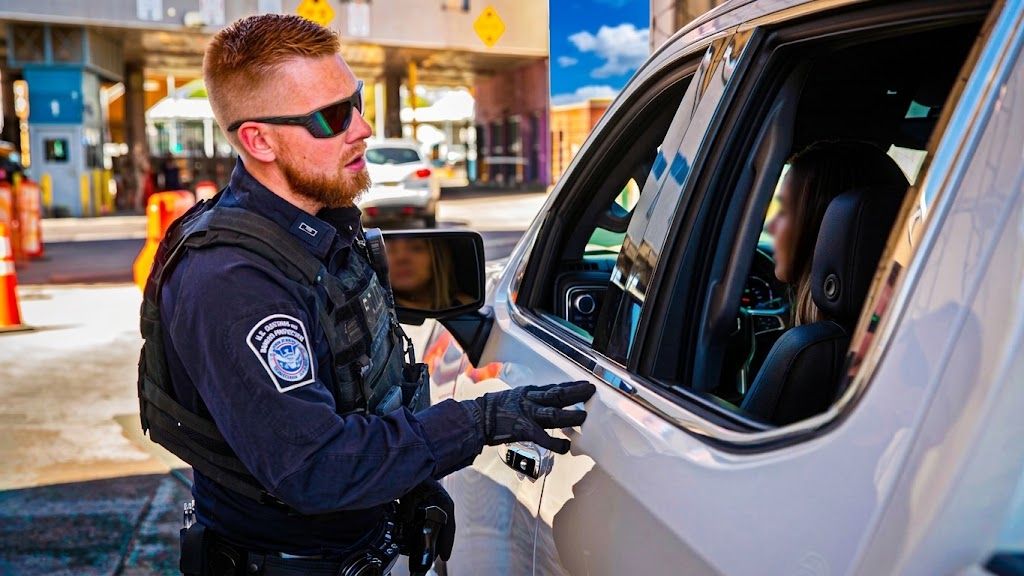 U.S. Customs and Border Protection officer speaking with a traveler in a vehicle at a U.S. border