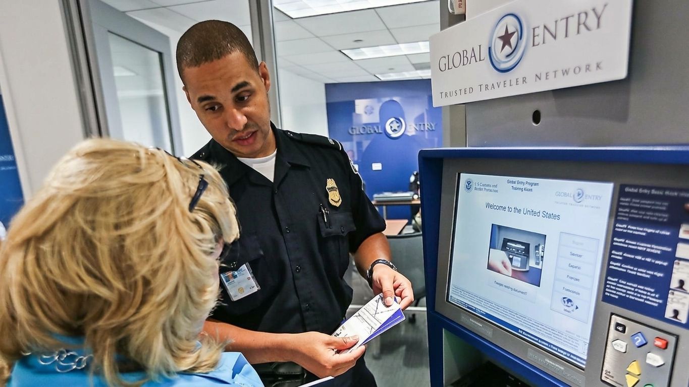 A U.S. Customs and Border Protection (CBP) officer providing a traveler directions regarding the use of a Global Entry kiosk at a U.S. airport