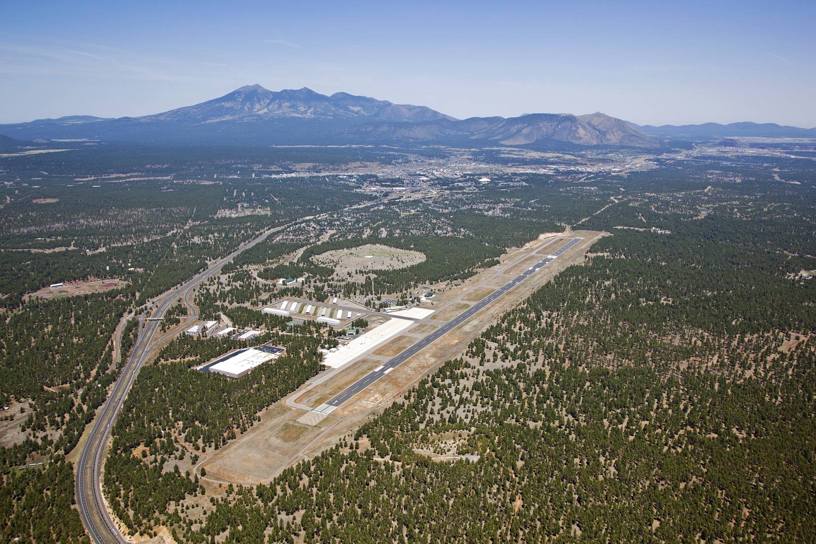 A view of Flagstaff, Arizona airport from above with downtown and the San Francisco Peaks in the distance, AZ, USA.